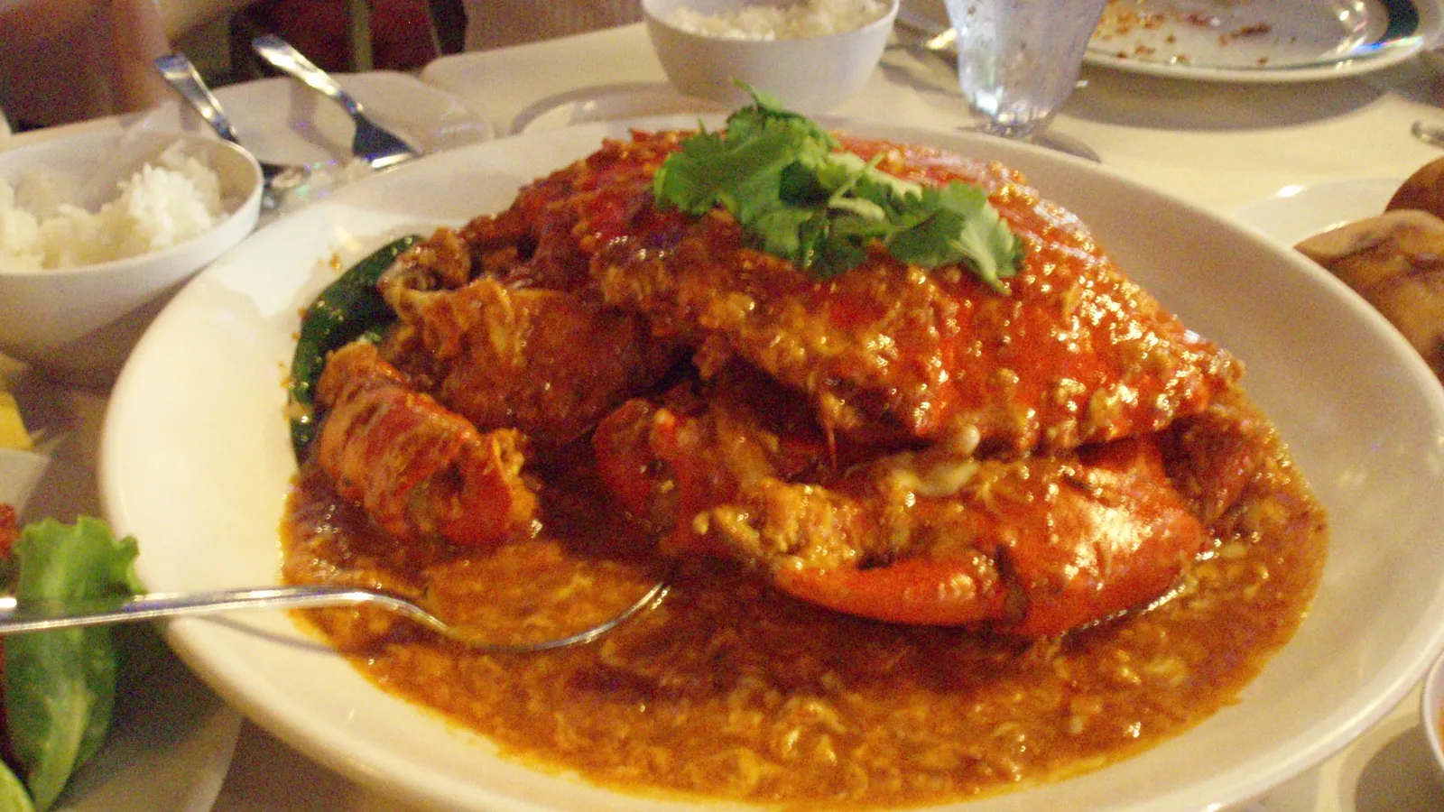 Plate of chilli crab in thick red-orange sauce, served with rice at a seafood dinner