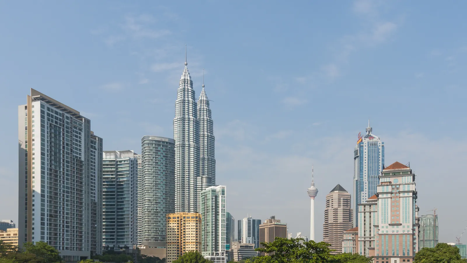Kuala Lumpur skyline with the Petronas Twin Towers and KL Tower rising above green trees on a clear day