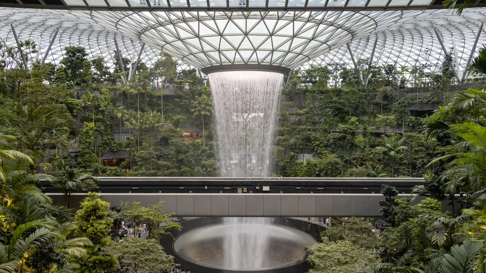 The Rain Vortex waterfall pouring through the glass dome into the Forest Valley at Jewel Changi Airport