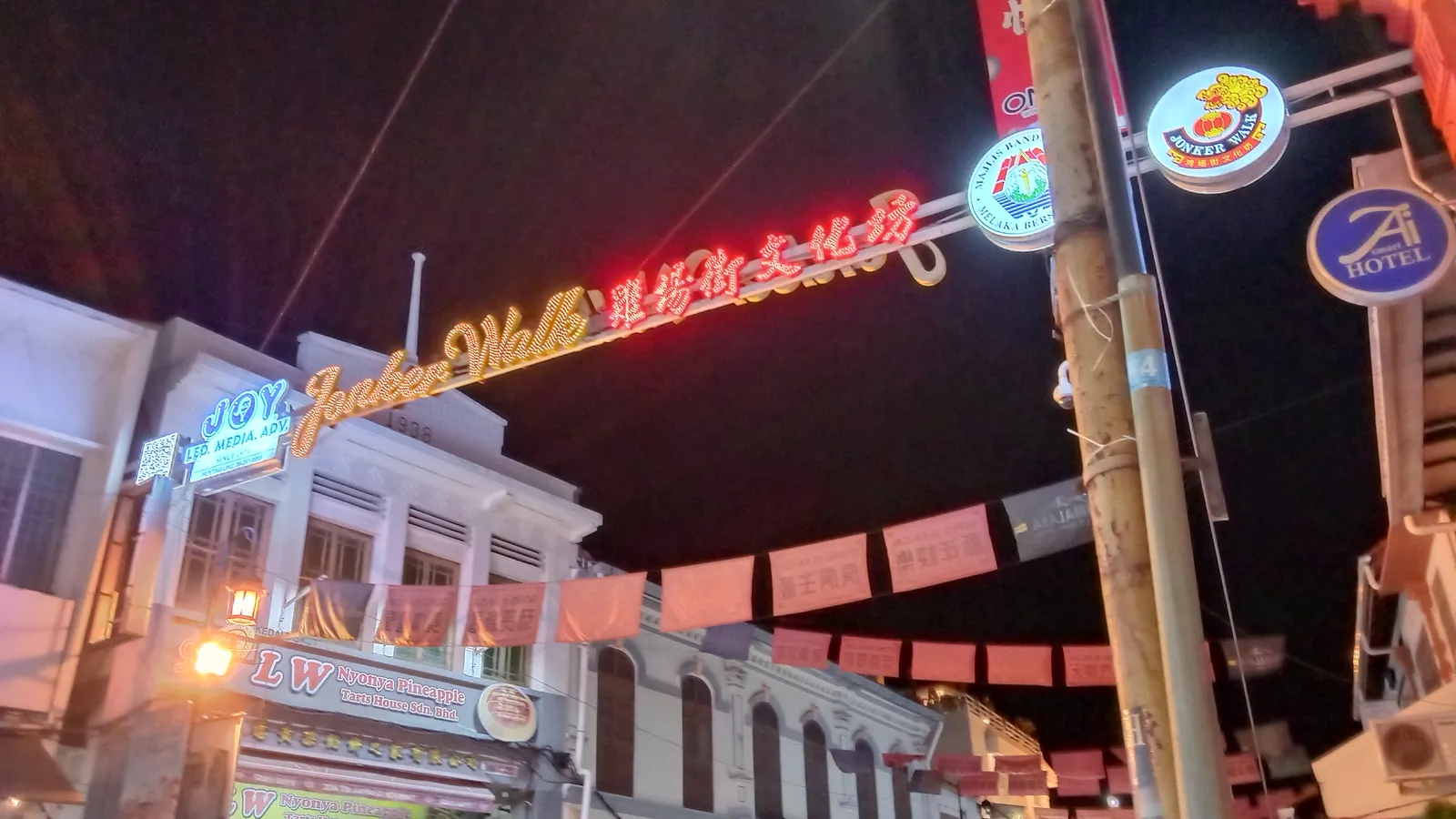 Neon Jonker Walk sign and red bunting over Jonker Street in Melaka at night