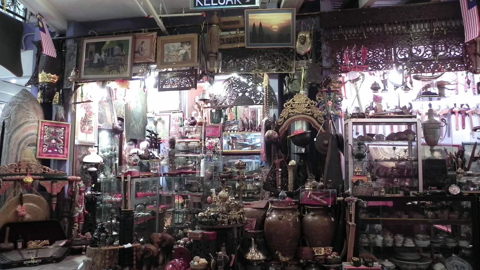 Souvenir and handicraft shop at Central Market in Kuala Lumpur, with carvings, pottery, framed pictures and brassware on display