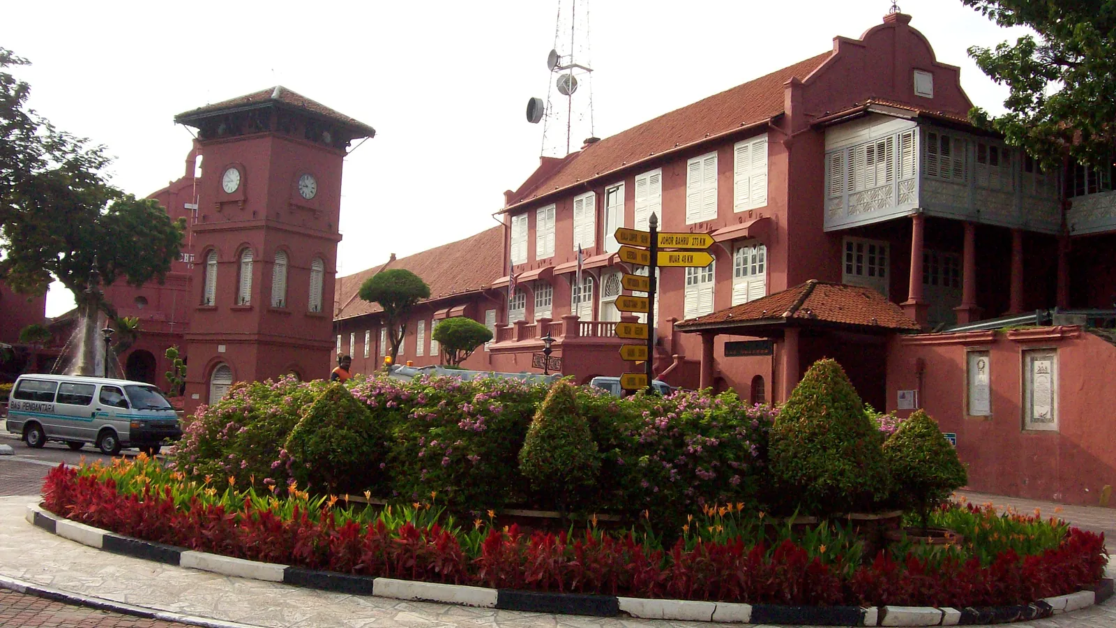 The red Stadthuys and clock tower on Dutch Square in Melaka's old town, with a flower bed in front
