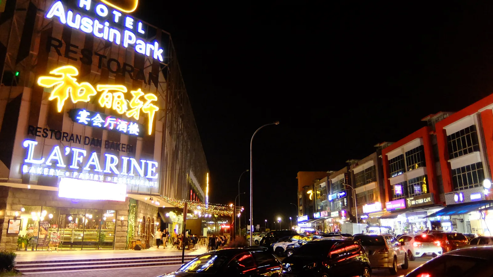 Neon restaurant and bakery signs lighting up a row of shophouses in Mount Austin, Johor Bahru, at night