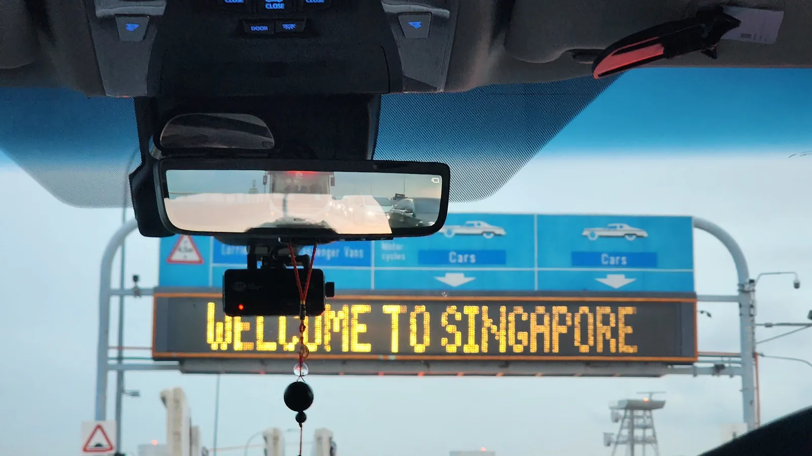 View from inside a car approaching the Singapore checkpoint car lanes, with a Welcome to Singapore sign overhead