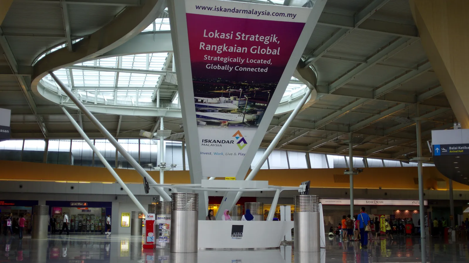 Inside the main hall of Senai International Airport in Johor, with its curved steel roof, skylight and shopfronts