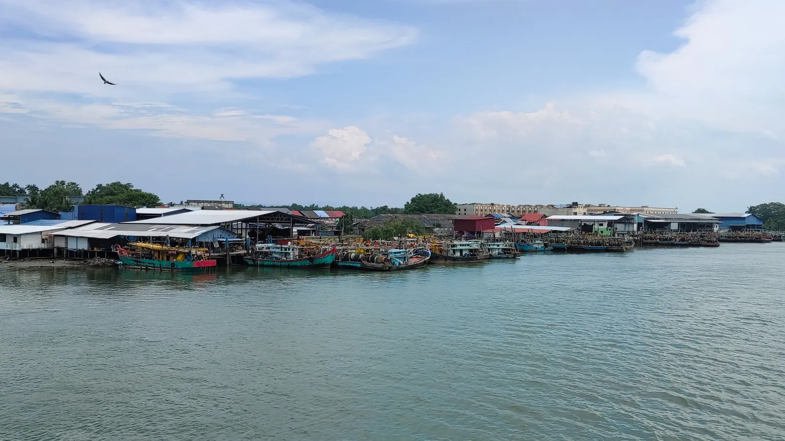 Fishing boats moored along the Endau River estuary, the Johor–Pahang border beside Tanjung Gemok, under a bright cloudy sky