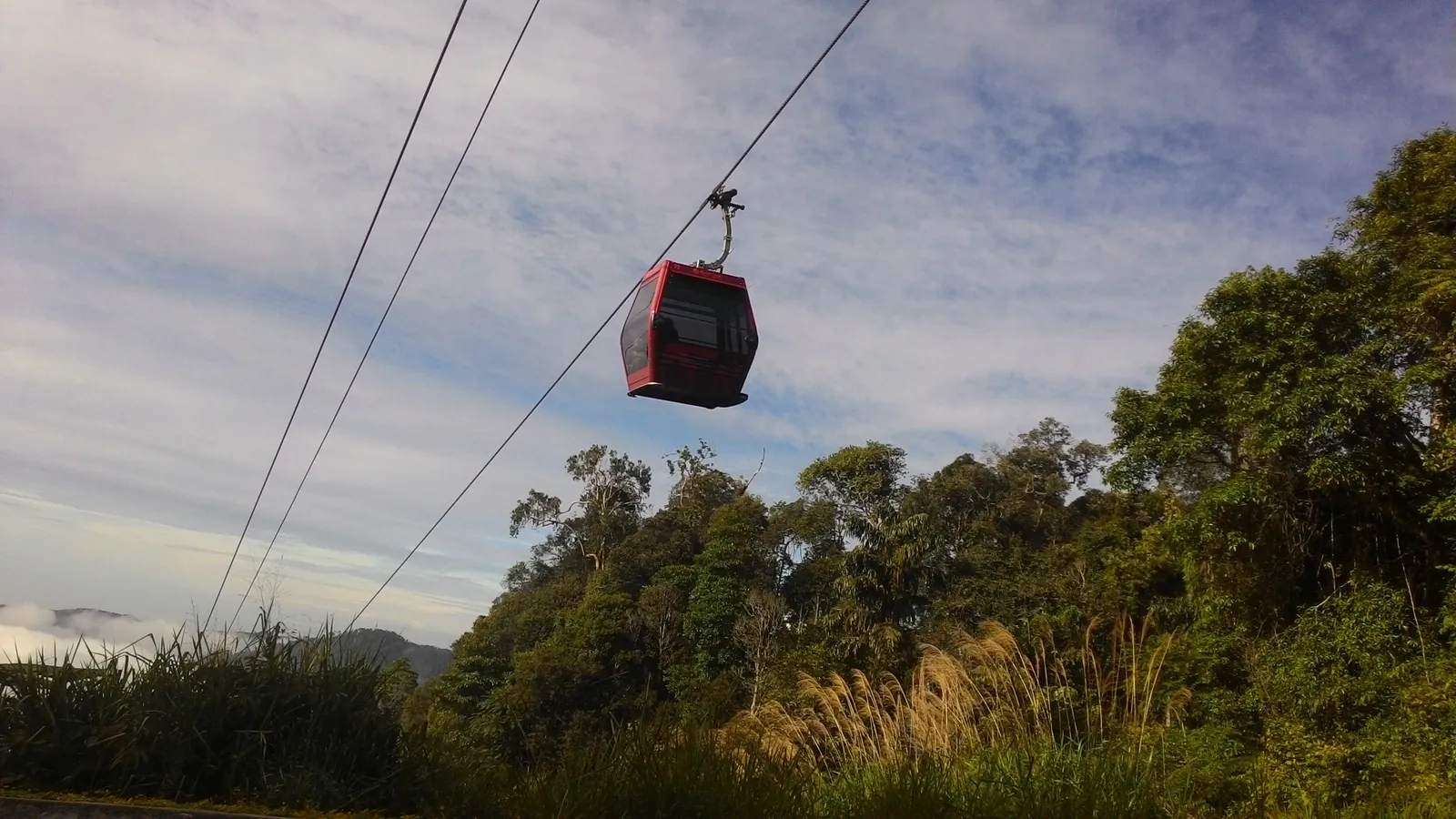 Red Awana SkyWay gondola cabin gliding over the rainforest of Genting Highlands