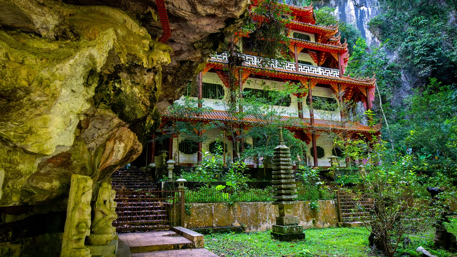 Red and white pagoda of Sam Poh Tong cave temple set against a limestone cliff in Ipoh