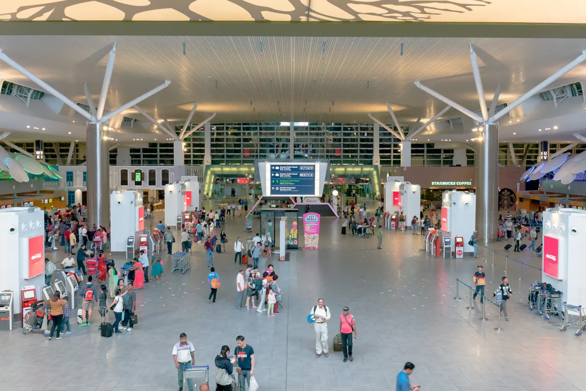 Busy departure hall with self check-in kiosks at KLIA2