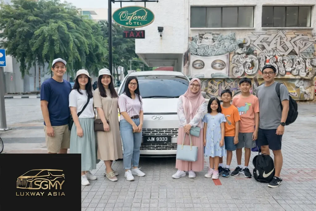Families on a Malacca day trip from Singapore, standing by a private MPV